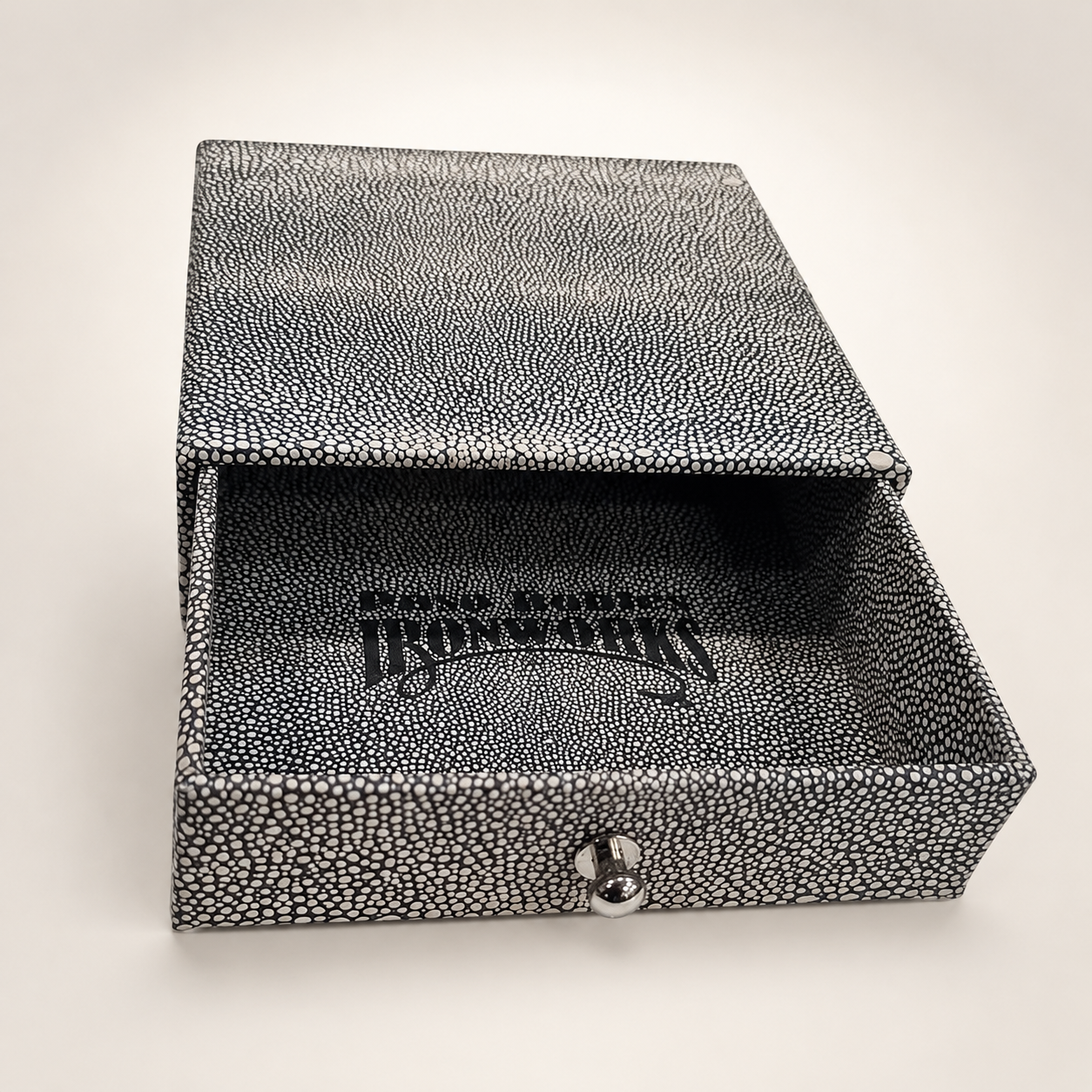 Open black-and-white textured rigid drawer box with a silver pull knob and branded interior