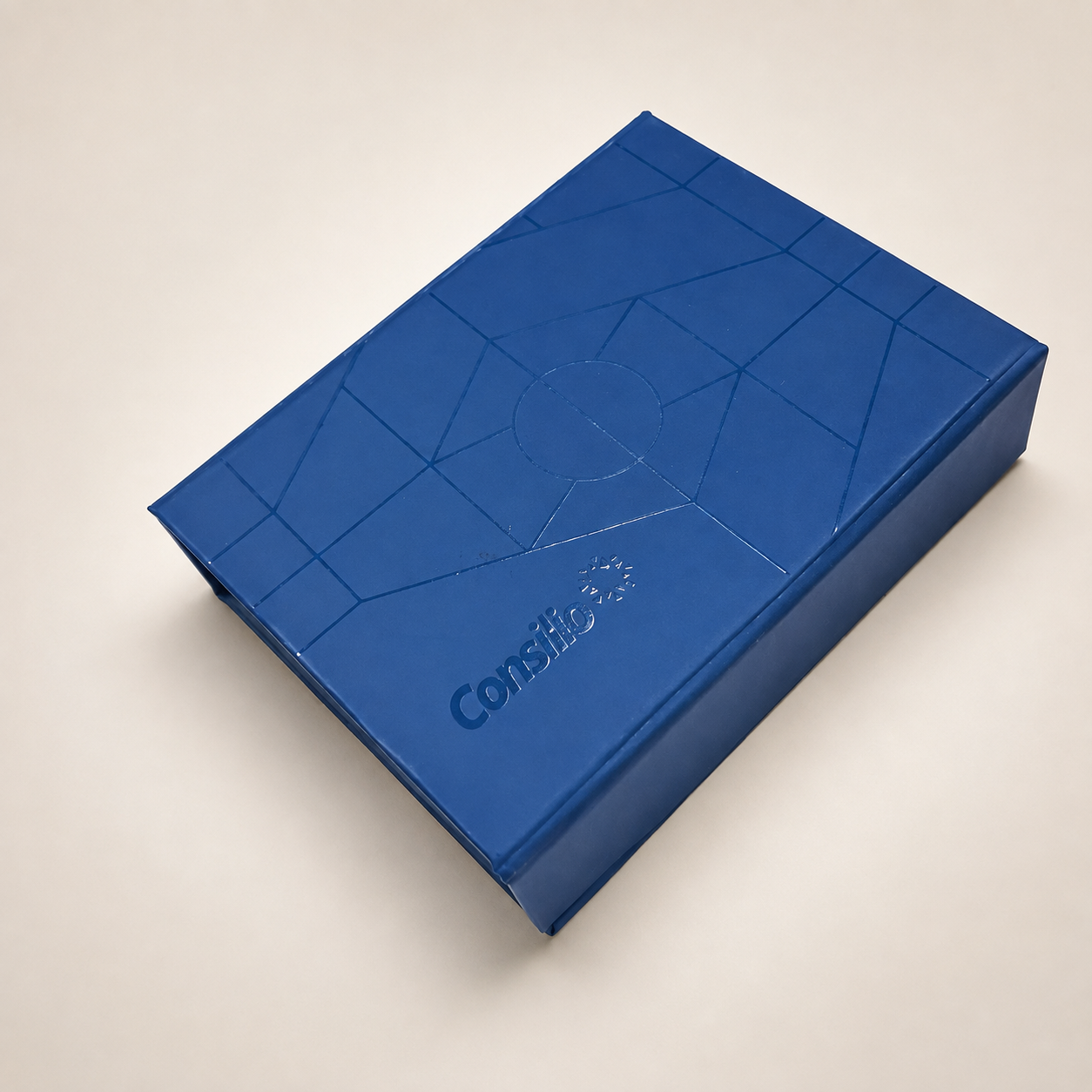 Closed royal-blue rigid presentation box with tonal geometric embossing and a glossy logo